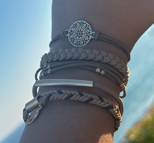 Close-up of a wrist wearing multiple bracelets with a blurred natural background