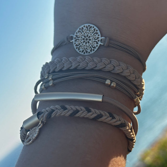 Close-up of a wrist wearing multiple bracelets with a blurred natural background